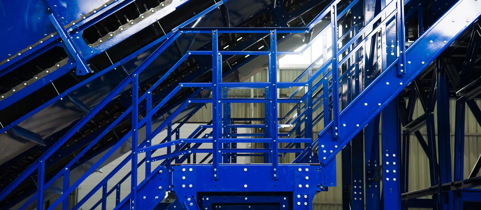 Blue steel access platform with bolted connections and handrails