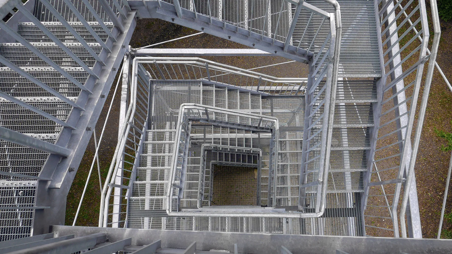 Multi-flight steel stairwell with open grating viewed from above