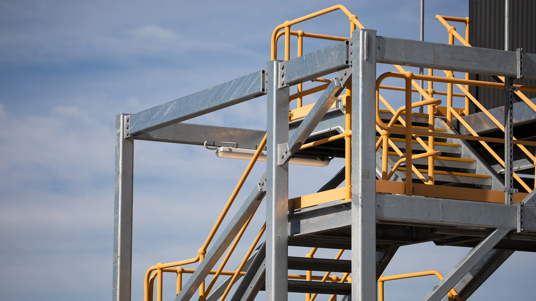Industrial steel access platform staircase with yellow safety guarding